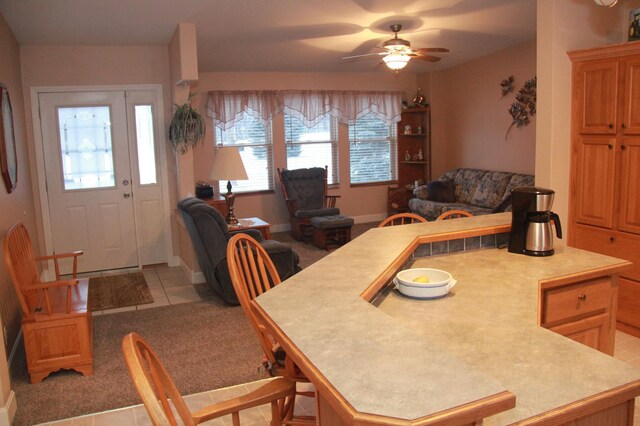 dining room with ceiling fan, light tile patterned flooring, baseboards, and light colored carpet