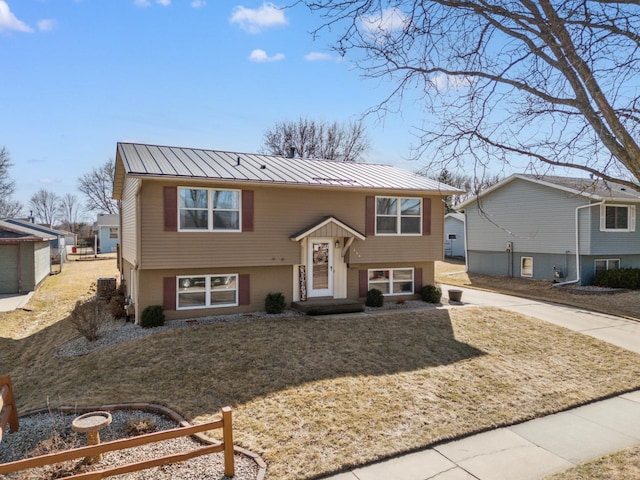 split foyer home featuring metal roof, a standing seam roof, a front lawn, and concrete driveway