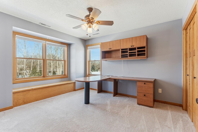 unfurnished office featuring light carpet, baseboards, visible vents, and ceiling fan