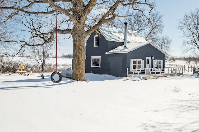 snow covered back of property featuring metal roof