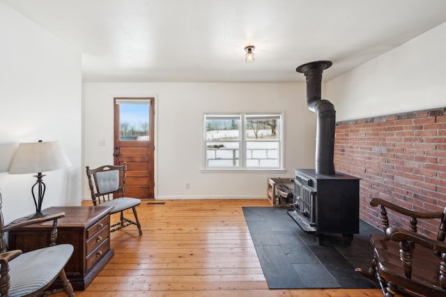 interior space with a wood stove, light wood-style flooring, and baseboards