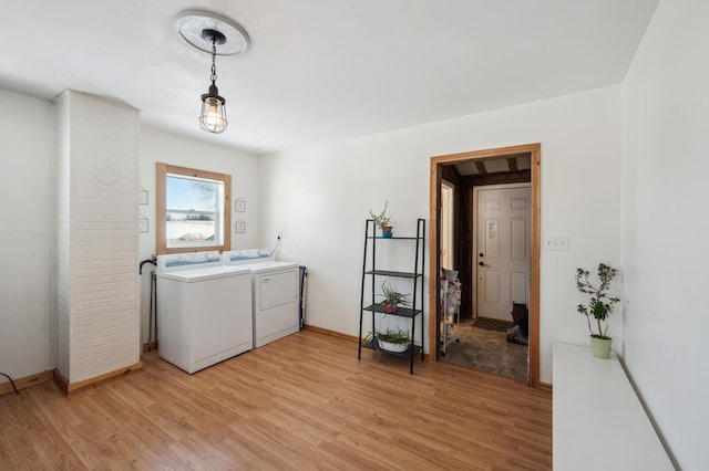 clothes washing area with laundry area, light wood-style flooring, and washer and clothes dryer