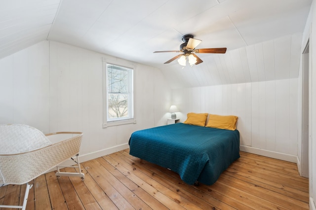 bedroom with light wood-style floors, vaulted ceiling, baseboards, and ceiling fan