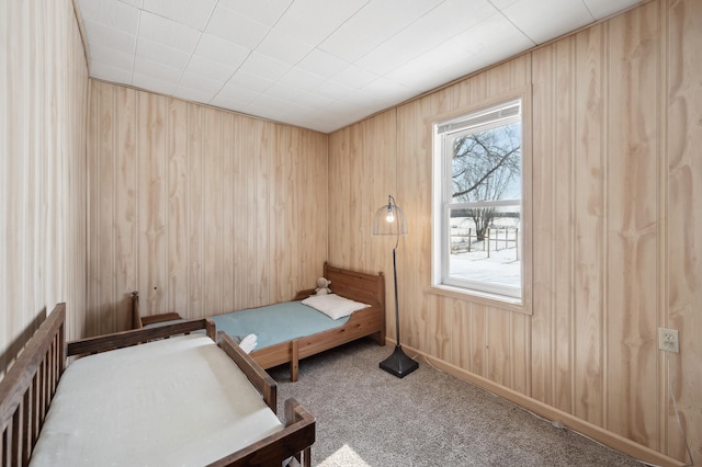 carpeted bedroom featuring wood walls