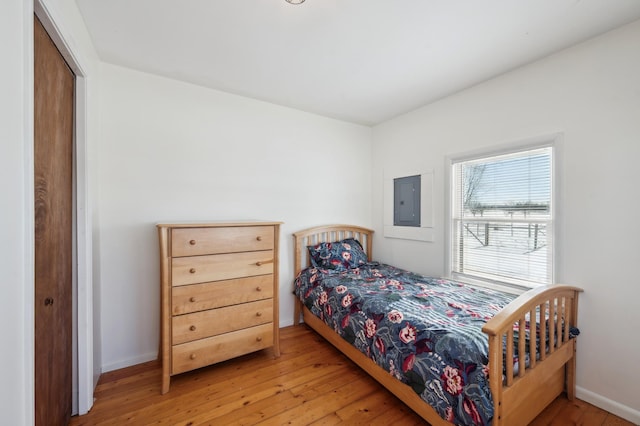 bedroom with electric panel, baseboards, and wood finished floors