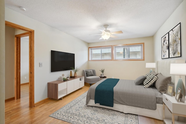 bedroom with a textured ceiling, ceiling fan, and light wood finished floors