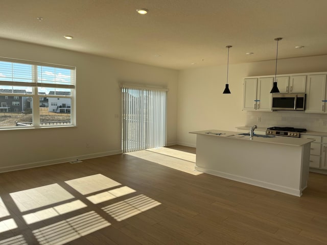 kitchen featuring hanging light fixtures, stainless steel microwave, light countertops, and white cabinets