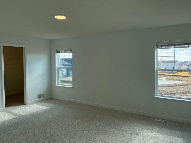 unfurnished room featuring carpet, visible vents, and baseboards