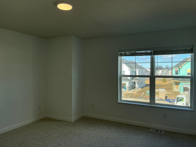 empty room featuring carpet, visible vents, and baseboards