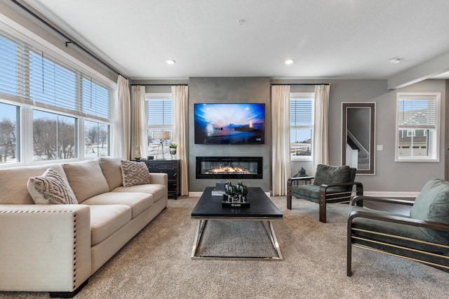 carpeted living room with recessed lighting, a large fireplace, and baseboards