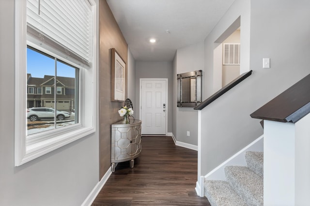 foyer featuring dark wood-type flooring, visible vents, baseboards, and stairs