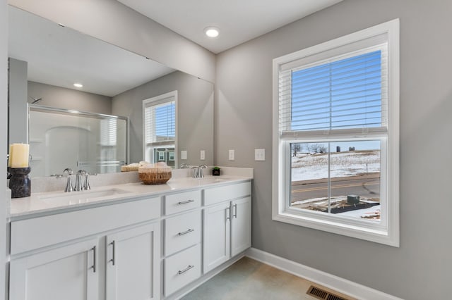 bathroom featuring a sink, a shower stall, baseboards, and double vanity