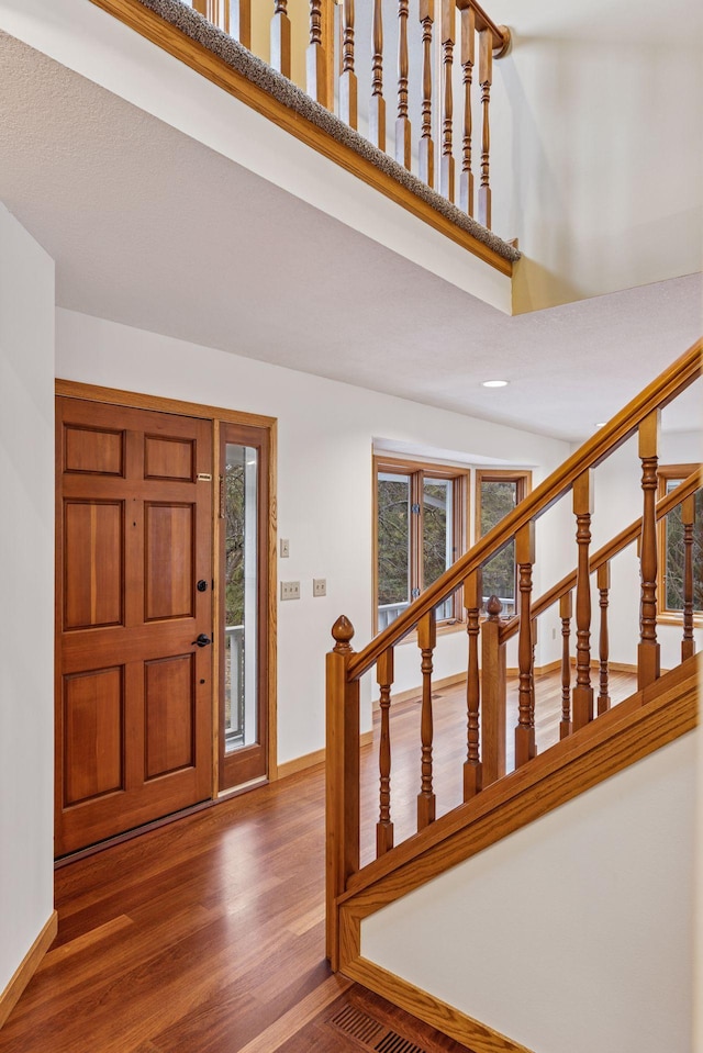 entryway with stairway, baseboards, visible vents, and wood finished floors