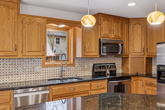 kitchen featuring pendant lighting, a sink, dark stone countertops, tasteful backsplash, and appliances with stainless steel finishes