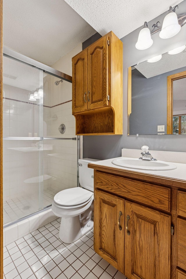 bathroom featuring vanity, a shower stall, toilet, and a textured ceiling