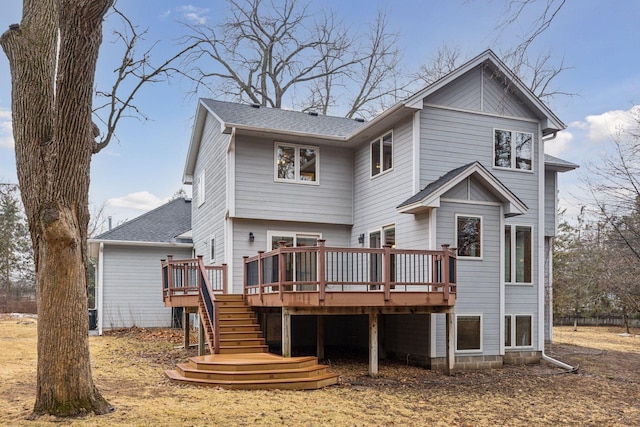 back of property with a deck, stairs, and roof with shingles