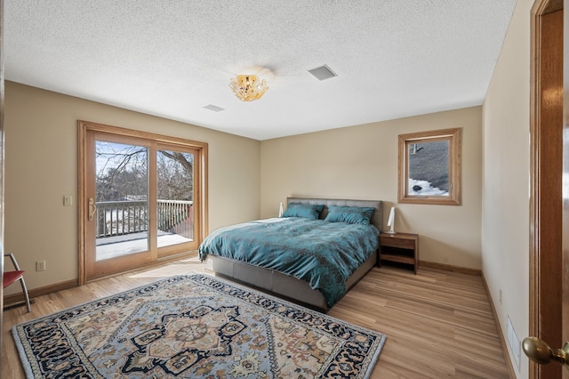 bedroom featuring a textured ceiling, visible vents, baseboards, access to exterior, and light wood-type flooring