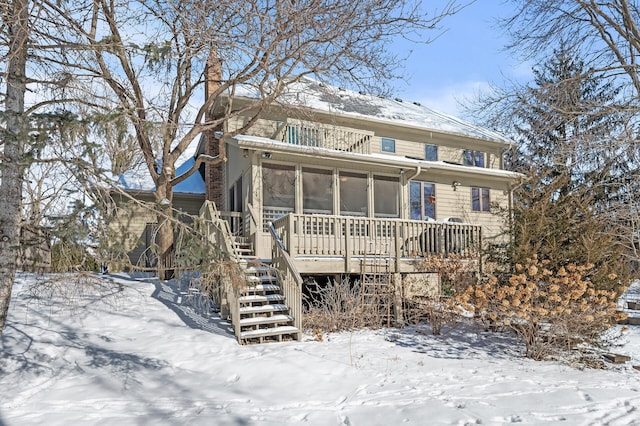 view of front of home featuring stairs, a chimney, and a sunroom