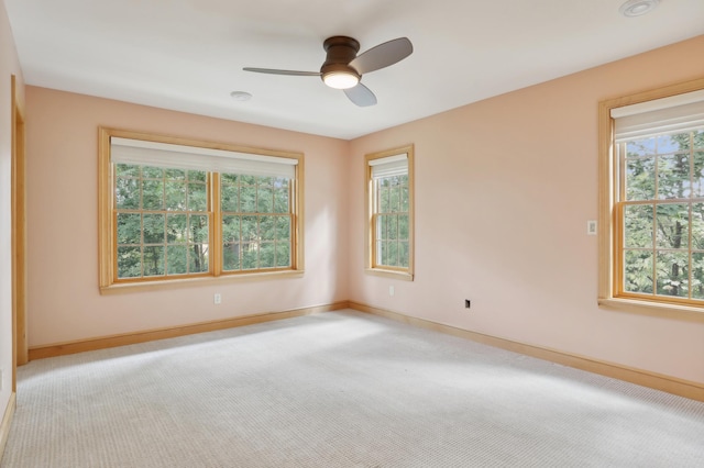 spare room featuring a ceiling fan, a healthy amount of sunlight, light carpet, and baseboards