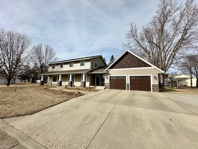 view of front of home with stone siding, covered porch, an attached garage, and driveway