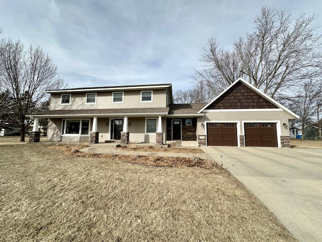 view of front of home featuring a garage, stone siding, covered porch, and driveway