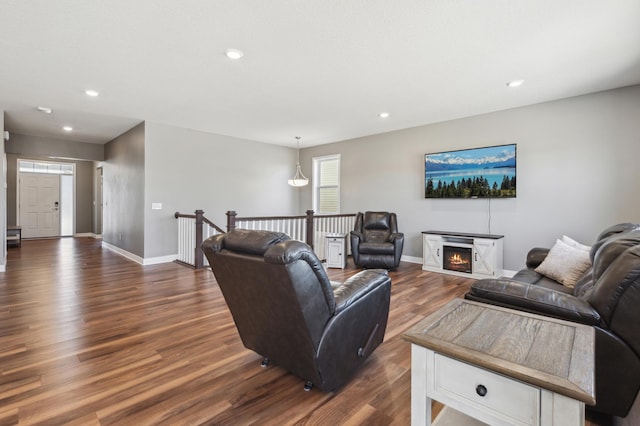 living area with recessed lighting, dark wood finished floors, a lit fireplace, and baseboards