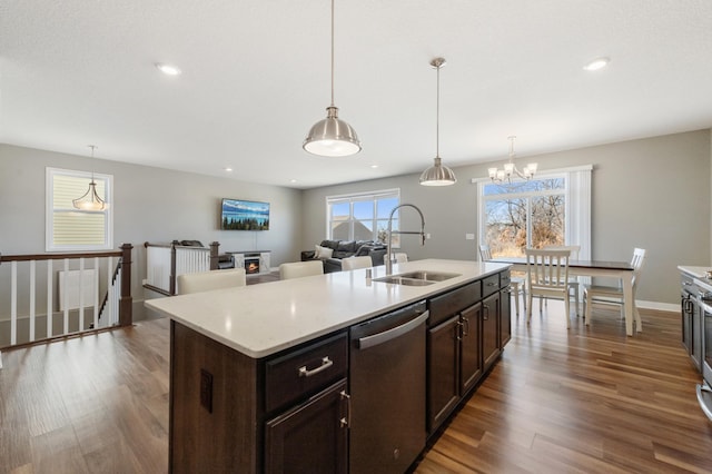 kitchen with a center island with sink, dishwasher, wood finished floors, dark brown cabinets, and a sink