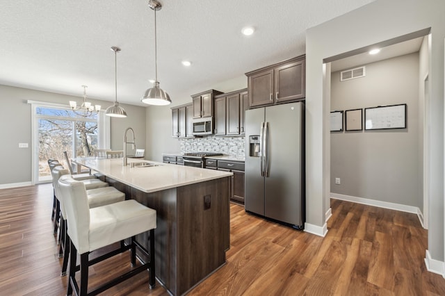 kitchen with stainless steel appliances, light countertops, visible vents, decorative backsplash, and dark brown cabinets