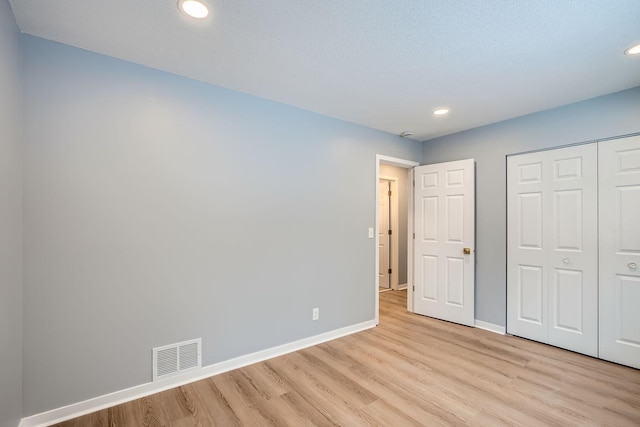 unfurnished bedroom with a closet and light hardwood / wood-style floors