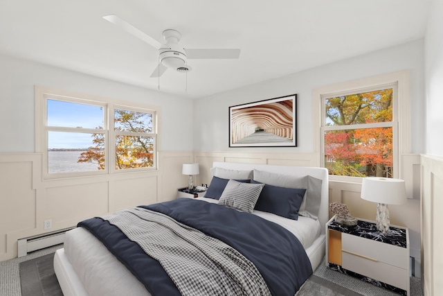 carpeted bedroom with a decorative wall, wainscoting, and a baseboard radiator