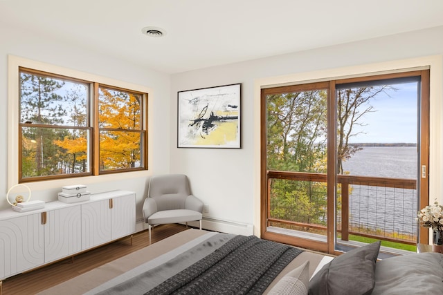 bedroom with visible vents, wood finished floors, baseboard heating, and multiple windows