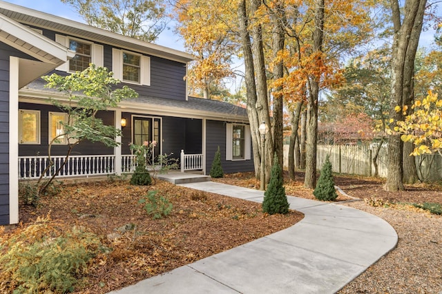 traditional home with covered porch and a shingled roof