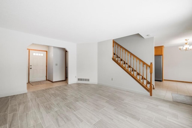 unfurnished living room featuring visible vents, stairway, a chandelier, light wood-type flooring, and baseboards