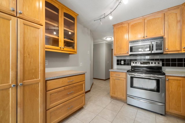 kitchen with light countertops, appliances with stainless steel finishes, backsplash, and glass insert cabinets