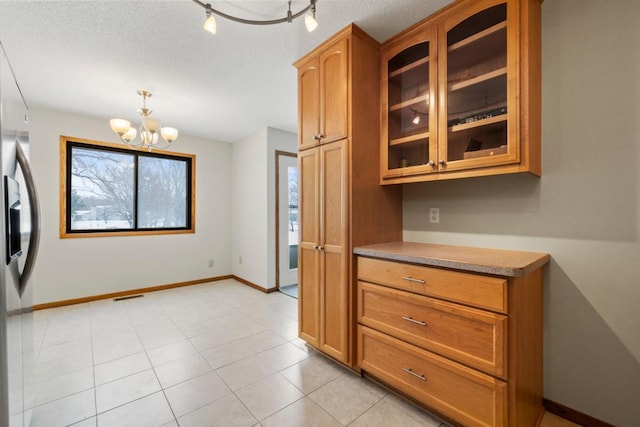 kitchen with baseboards, visible vents, glass insert cabinets, light countertops, and stainless steel refrigerator with ice dispenser