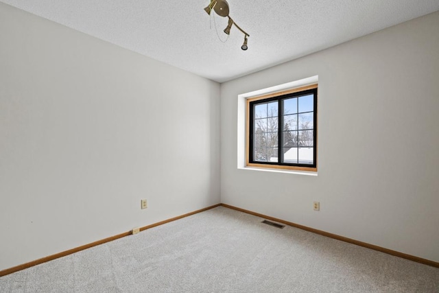 unfurnished room featuring carpet floors, visible vents, baseboards, and a textured ceiling