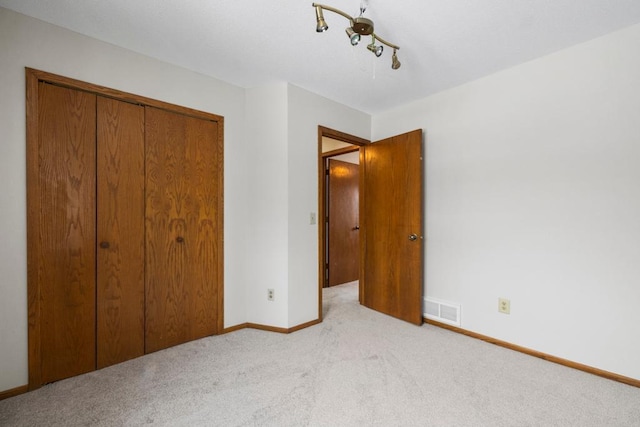 unfurnished bedroom featuring light carpet, baseboards, visible vents, and a closet