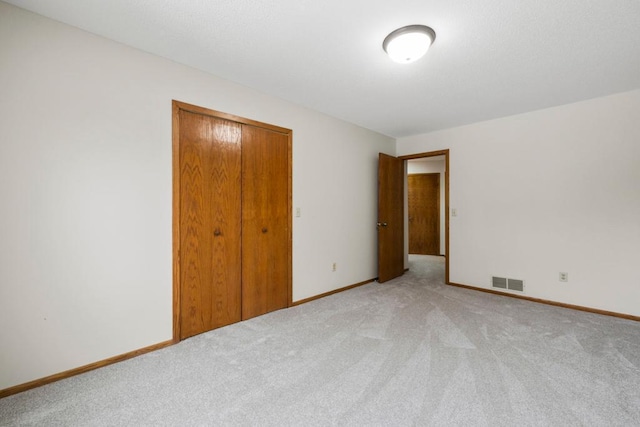 unfurnished bedroom featuring light colored carpet, a closet, visible vents, and baseboards