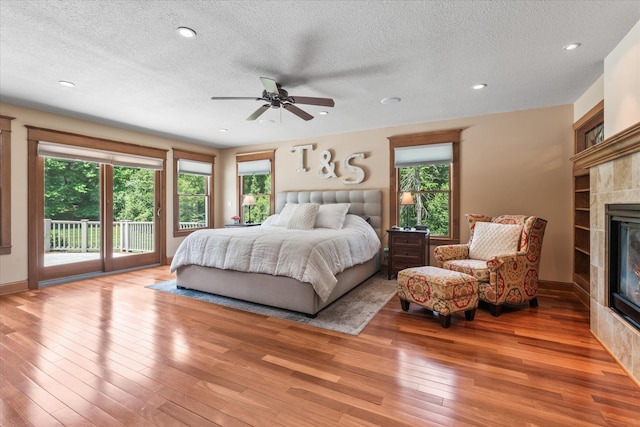 6388 Jasmine Ave N, Stillwater, MN 55082 - bedroom featuring a tiled fireplace, access to outside, light wood-style flooring, a textured ceiling, and recessed lighting