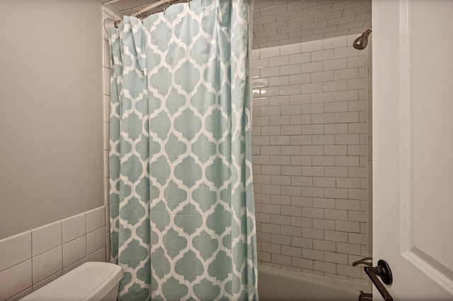 bathroom featuring shower / tub combo and toilet