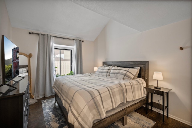 bedroom featuring dark wood-type flooring, lofted ceiling, and baseboards