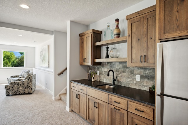 bar featuring sink, backsplash, a textured ceiling, stainless steel refrigerator, and light carpet