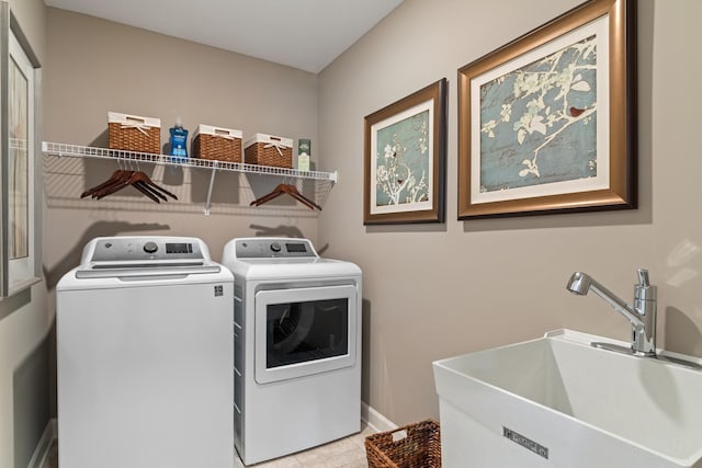 laundry room with light tile patterned flooring, washer and dryer, and sink