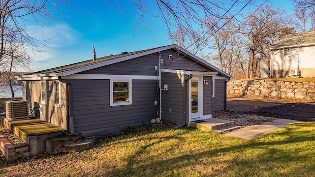 rear view of property with central air condition unit and a yard