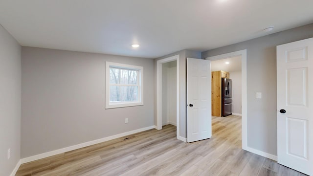 unfurnished bedroom featuring light wood-style flooring, recessed lighting, visible vents, baseboards, and stainless steel refrigerator with ice dispenser