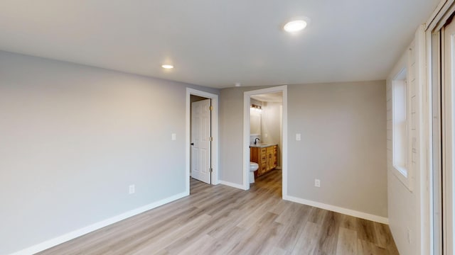 unfurnished bedroom with light wood-style floors, recessed lighting, ensuite bath, and baseboards