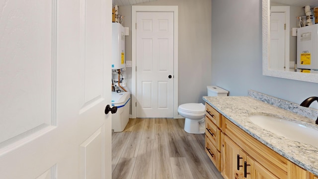 bathroom with water heater, toilet, wood finished floors, and vanity