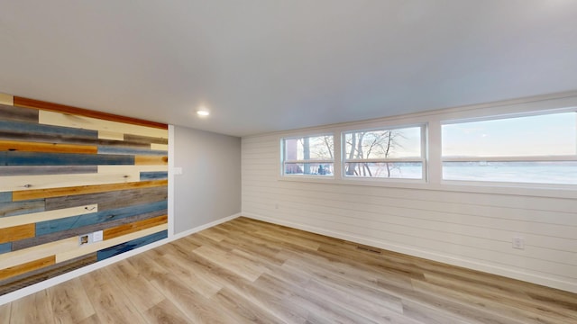 spare room with recessed lighting, visible vents, light wood-style floors, wooden walls, and baseboards