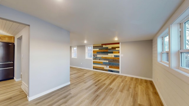 unfurnished room with a wealth of natural light, light wood-style flooring, and baseboards