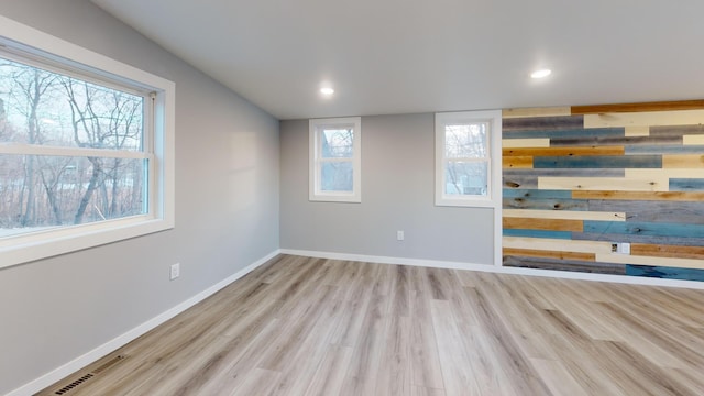 empty room with visible vents, plenty of natural light, baseboards, and wood finished floors